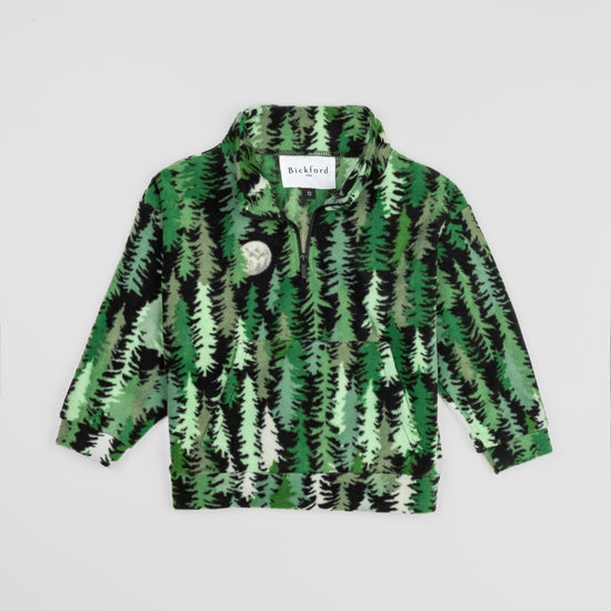 Bickford USA Youth Quarter-Zip fleece pullover in the Eastern Pine colorway, laid flat on a light gray background, featuring an all-over print of layered pine trees in shades of green, black, and cream with a moon motif, funnel collar, quarter-zip closure, and front kangaroo pocket.