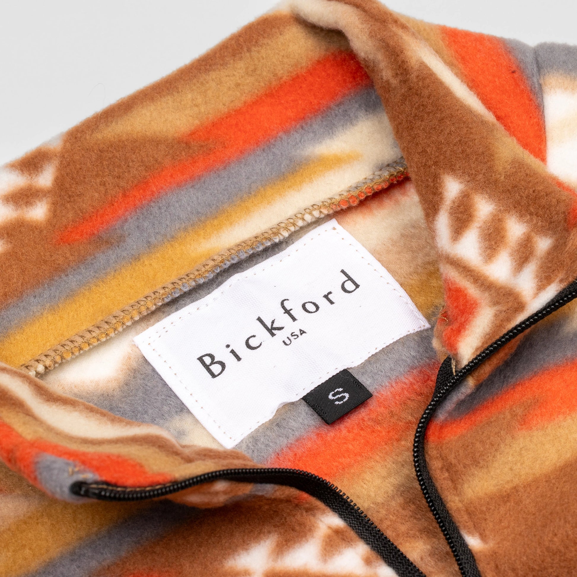 Close-up detail of the Heritage Trail Youth Quarter-Zip showing the open funnel collar with the Bickford USA label and size tag visible, with the southwestern stripe and motif print visible on the inner collar and the black zipper.
