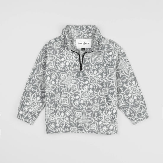 Bickford USA Youth Quarter-Zip fleece pullover in the Snowflake colorway, laid flat on a light gray background, featuring an all-over ornate snowflake and medallion print in grey and white, with a funnel collar, quarter-zip closure, and front kangaroo pocket.
