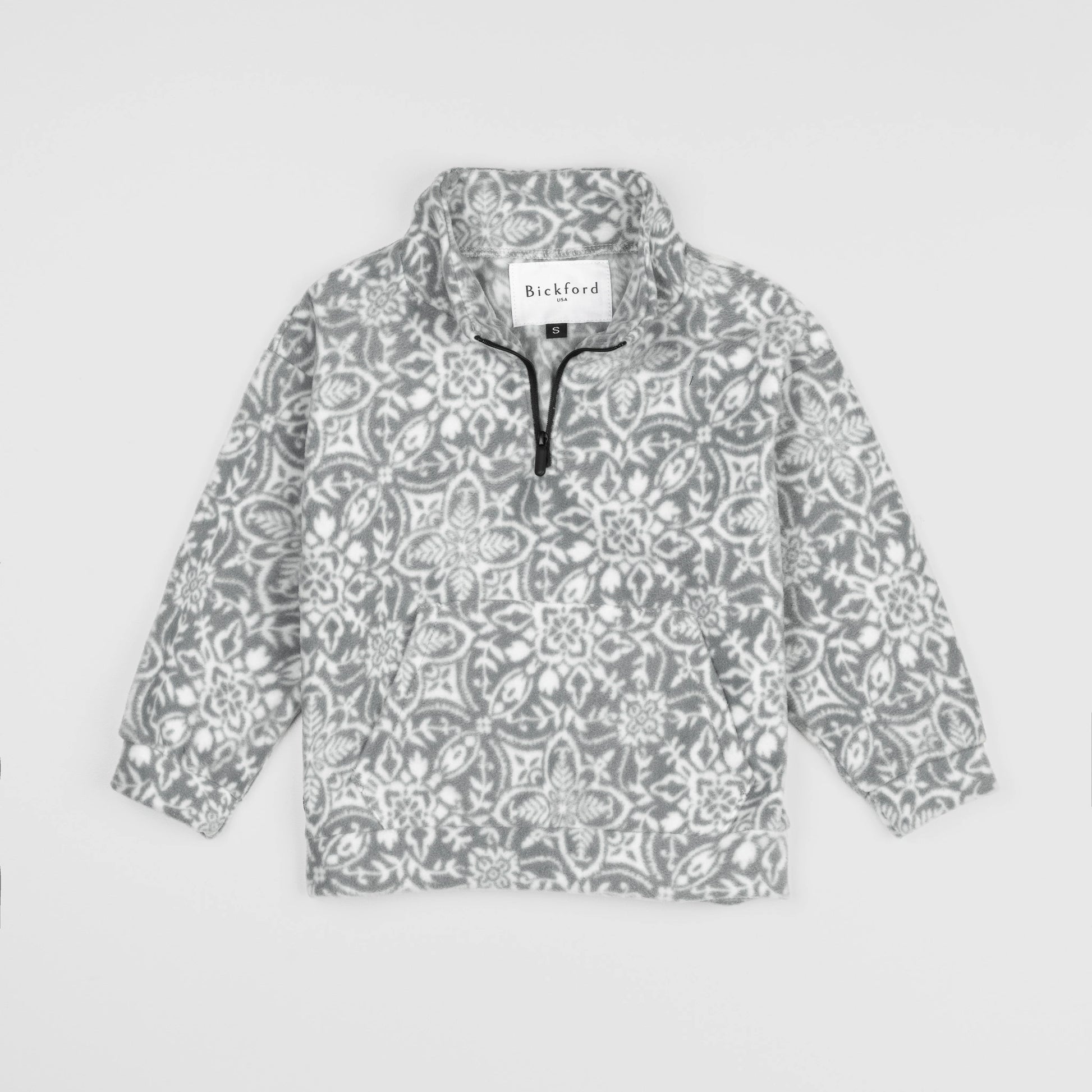 Bickford USA Youth Quarter-Zip fleece pullover in the Snowflake colorway, laid flat on a light gray background, featuring an all-over ornate snowflake and medallion print in grey and white, with a funnel collar, quarter-zip closure, and front kangaroo pocket.