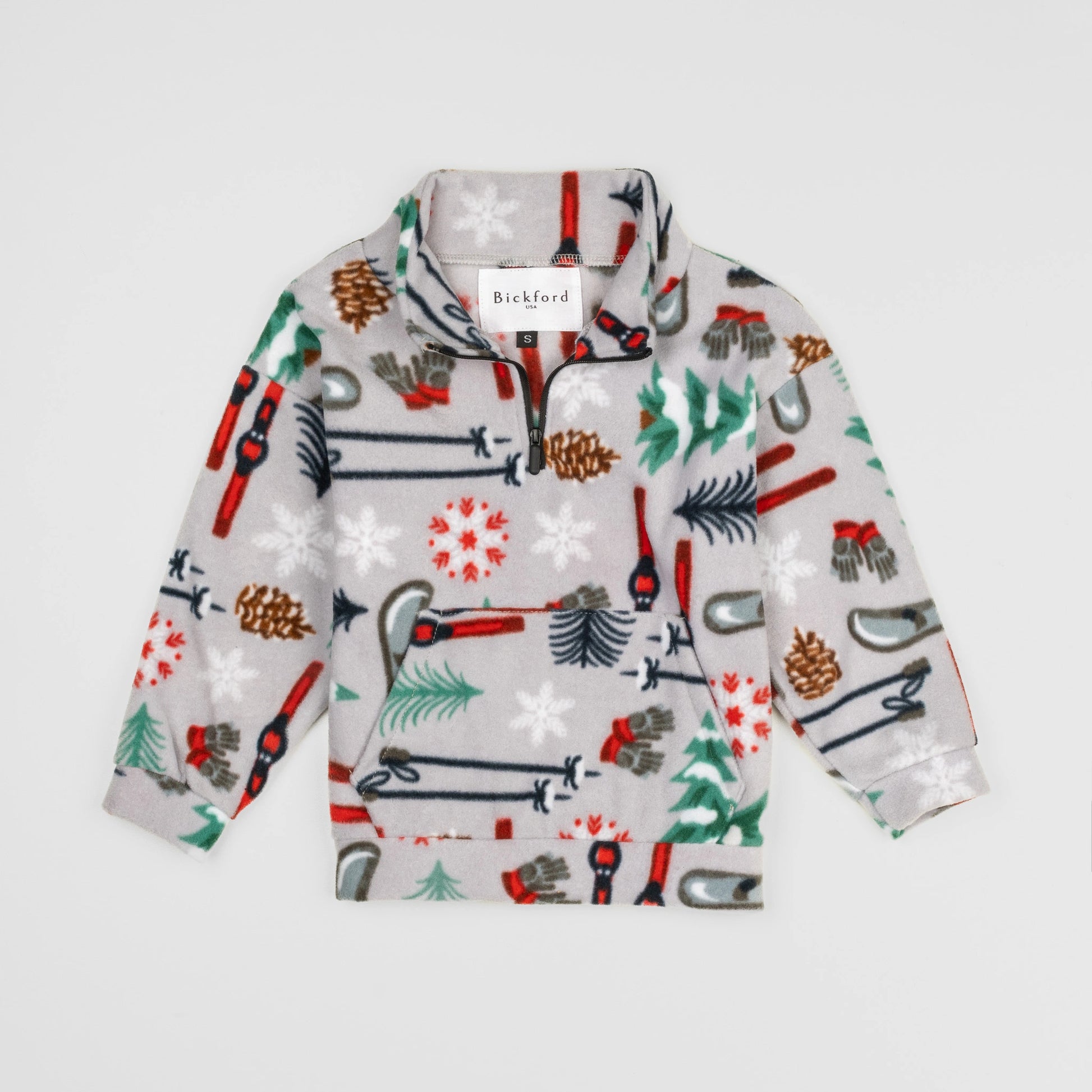 Bickford USA Youth Quarter-Zip fleece pullover in the Sugarbush colorway, laid flat on a light gray background, featuring an all-over winter sports print with skis, ski poles, ice skates, mittens, snowflakes, pinecones, and pine trees on a light grey background, with a funnel collar, quarter-zip closure, and front kangaroo pocket.