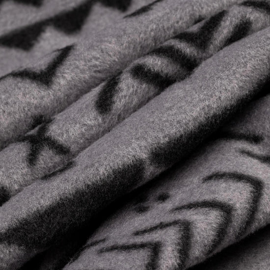 Close-up macro shot of soft fleece fabric in the Boulder colorway — a gray base with a black allover geometric and tribal print — showing the plush texture and depth of the pile.