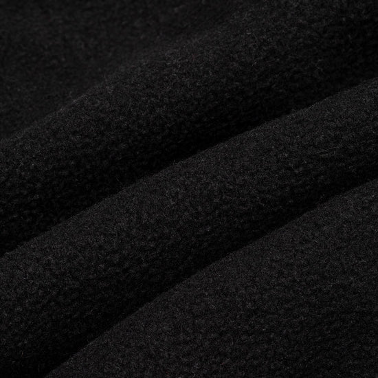 Close-up macro shot of solid black fleece fabric showing the dense, soft pile texture with subtle surface variation.
