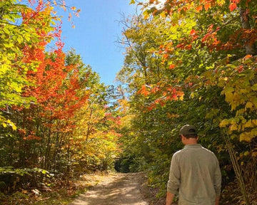 Bickford USA founder Luke walking on a forest road surrounded by autumn foliage in New England.
